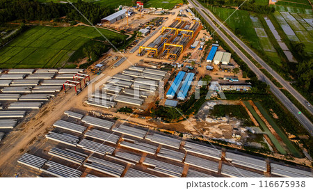Aerial view of a new road development or highway under construction. Top view from a drone over road construction workers amidst mountains. Construction Site with Cranes and Heavy Equipment. Aerial view of a new road development or highway under construction. Top view from a drone over road construction workers amidst mountains. Construction Site with Cranes and Heavy Equipment. 116675938