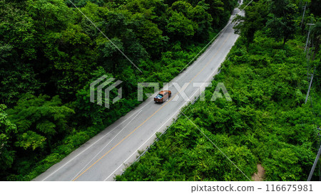 Aerial view of countryside asphalt road with car and green forest. Drive on the road between green forests. 116675981