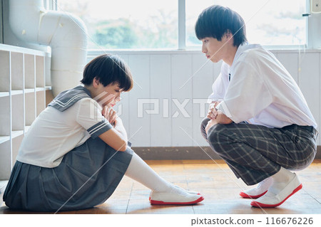 A high school boy reaching out to a depressed female student 116676226