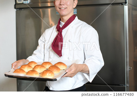 Smiling Asian man making bread in the kitchen Smiling Asian man making bread in the kitchen 116677480