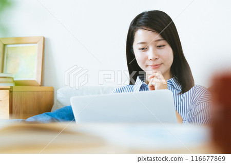 A woman who plays a personal computer in the living room 116677869