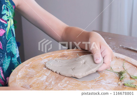 Young teenage girl molding houses out of clay. Hobbies and tools. Creativity for children, education.  116678801