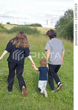 Dad and mum run with child along path in summer in countryside. Nature and sunlight. Sunset. . High quality 4k footage Dad and mum run with child along path in summer in countryside. Nature and sunlight. Sunset. . High quality 4k footage 116678819