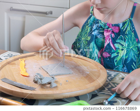 Young teenage girl molding houses out of clay. Hobbies and tools. Creativity for children, education. Young teenage girl molding houses out of clay. Hobbies and tools. Creativity for children, education. 116678869