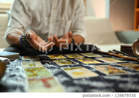 Fortune teller reading tarot cards on table with a mystical cloth. Forecasting and divination concept Fortune teller reading tarot cards on table with a mystical cloth. Forecasting and divination concept 116679338