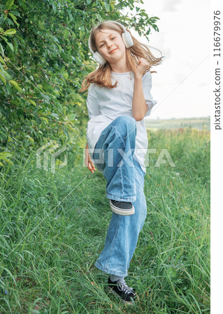 A child  with headphones listening to music and dancing 116679976