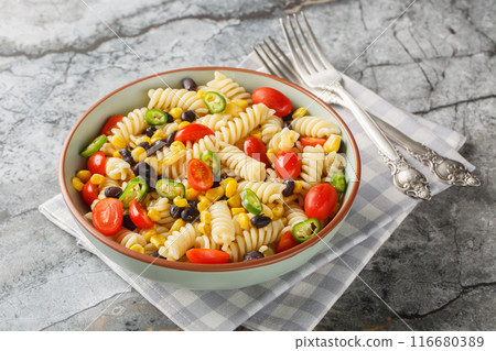 Fresh homemade colorful vegan fusilli pasta salad with beans, corn, tomato and jalapeno close-up in a plate. Horizontal 116680389