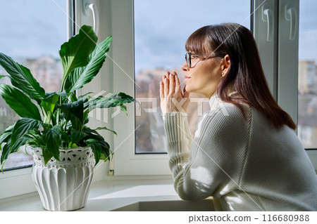 Beautiful happy middle aged woman looking out the window 116680988
