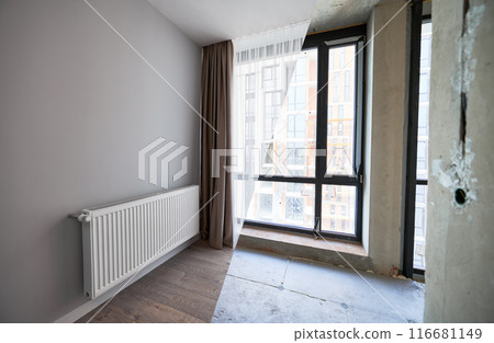 Comparison of apartment flat before and after restoration or refurbishment. Photo collage of old room with large windows and new renovated room with heating radiator, parquet floor and white walls. Comparison of apartment flat before and after restoration or refurbishment. Photo collage of old room with large windows and new renovated room with heating radiator, parquet floor and white walls. 116681149