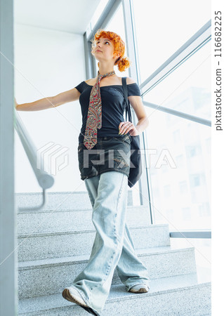 portrait red-haired attractive young woman on staircase, against backdrop large display window portrait red-haired attractive young woman on staircase, against backdrop large display window 116682225