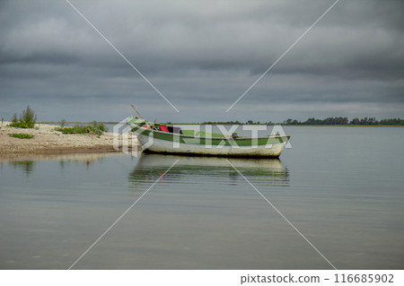 lonely fishing boat docked in calm sea. 116685902