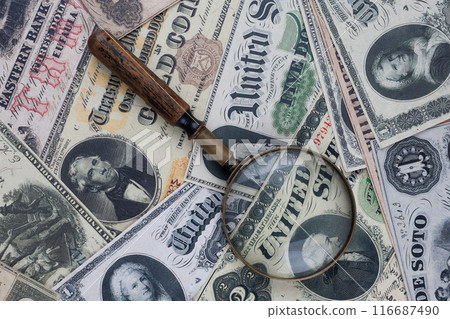US banknotes and silver certificates with silver dollar coins and magnifying glass US banknotes and silver certificates with silver dollar coins and magnifying glass 116687490