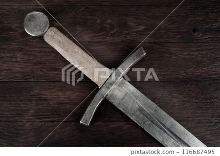 Medieval sword on wooden background. 116687495