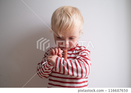 Little girl eating tasty sausage on white background Little girl eating tasty sausage on white background 116687650