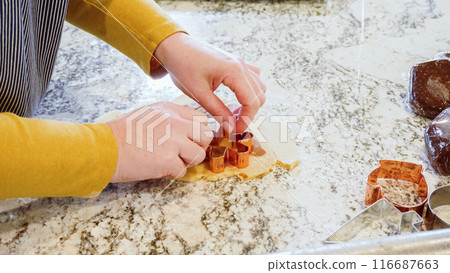 Using various festive cookie cutters, we're cutting out charming gingerbread cookies from the rolled dough on the sleek marble counter, bringing holiday cheer to the modern kitchen. Using various festive cookie cutters, we're cutting out charming gingerbread cookies from the rolled dough on the sleek marble counter, bringing holiday cheer to the modern kitchen. 116687663