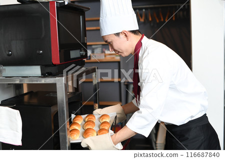 Young man preparing bread in the oven in the kitchen 116687840