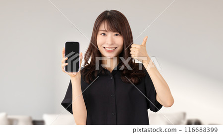 A smiling Japanese woman holding a smartphone and making a "Like!" pose A smiling Japanese woman holding a smartphone and making a "Like!" pose 116688399