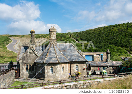 位於南威爾斯郊區的一棟歷史悠久的石頭建築，周圍環繞著綠樹，藍天下有蓬鬆的雲。 116688530