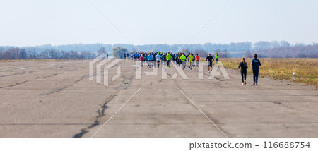 A large crowd is sprinting across the airstrip, taking part in a sporting event 116688754