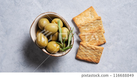 juicy olives with rosemary in Minsk on a blue background with slices of bread close up.  116688849