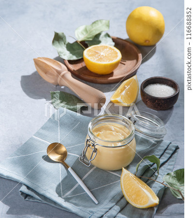 homemade lemon curd in a glass jar with lemon slices on a blue background. homemade lemon curd in a glass jar with lemon slices on a blue background. 116688852