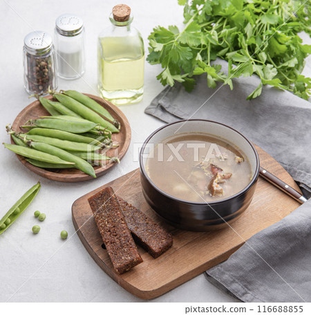 Pea soup with smoked meat in a bowl on a wooden board with croutons, fresh vegetables, herbs Pea soup with smoked meat in a bowl on a wooden board with croutons, fresh vegetables, herbs 116688855