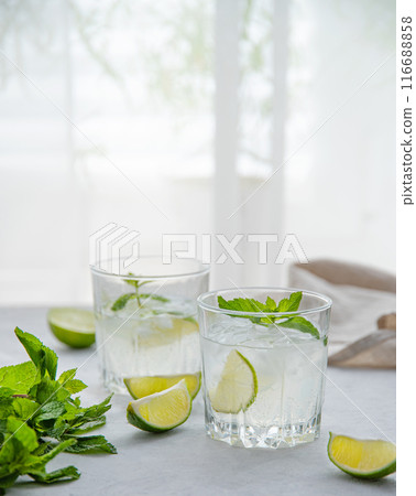 two glasses of lime lemonade mojito on the table with lime slices and mint two glasses of lime lemonade mojito on the table with lime slices and mint 116688858
