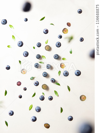 Concept flat lay with a  few juicy blueberries levitation with green leaves on yellow background 116688875