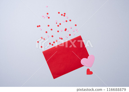 red paper envelope with free space for text with hearts and confetti on a gray background.  red paper envelope with free space for text with hearts and confetti on a gray background.  116688879