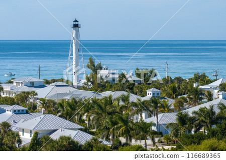 Expensive waterfront houses and white Boca Grande lighthouse on ocean shore. Small town on Gasparilla Island in southwest Florida. Premium housing development in the USA 116689365