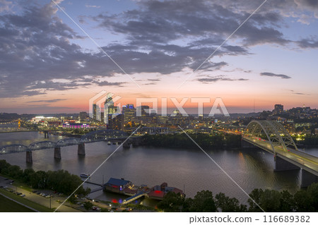 Driving cars on bridge highway near illuminated high skyscraper buildings in downtown district of Cincinnati, Ohio, USA. American city with business financial district at night 116689382