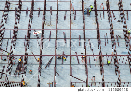 Construction site with hardhat workers assembling metal frame walls. Aerial view of large development area of commercial structure. Real estate market in the USA 116689428