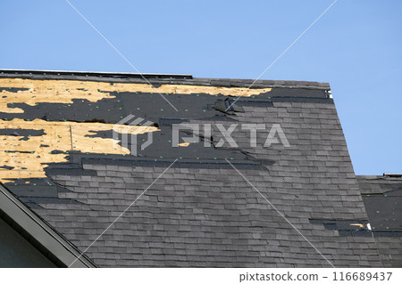 Consequences of natural disaster. Damaged house roof with missing shingles after hurricane Ian in Florida Consequences of natural disaster. Damaged house roof with missing shingles after hurricane Ian in Florida 116689437