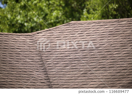 Closeup of house roof top covered with asphalt or bitumen shingles. Waterproofing of new building Closeup of house roof top covered with asphalt or bitumen shingles. Waterproofing of new building 116689477