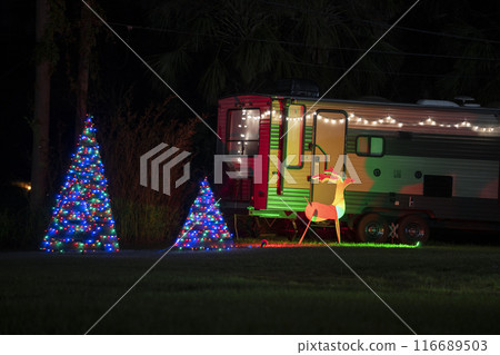 Camper van on front yard with brightly illuminated christmas decorations. Outside decor of caravan home for winter holidays Camper van on front yard with brightly illuminated christmas decorations. Outside decor of caravan home for winter holidays 116689503