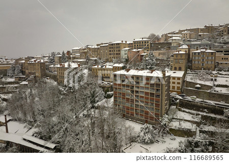 Aerial winter landscape of dense historic center of Thiers town in Puy-de-Dome department, Auvergne-Rhone-Alpes region in France. Rooftops of old buildings and narrow streets at snowfall Aerial winter landscape of dense historic center of Thiers town in Puy-de-Dome department, Auvergne-Rhone-Alpes region in France. Rooftops of old buildings and narrow streets at snowfall 116689565