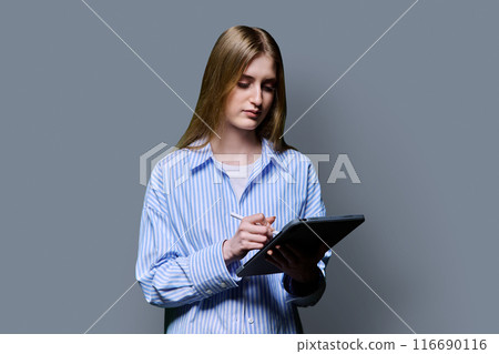 Teenage female student using digital tablet on gray studio background Teenage female student using digital tablet on gray studio background 116690116