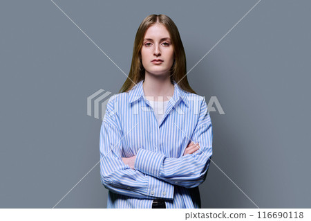 Portrait of teenage serious female with crossed arms on grey background Portrait of teenage serious female with crossed arms on grey background 116690118