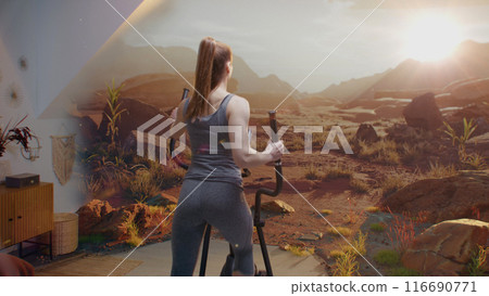 Sportswoman wearing VR headset trains on orbitrek simulator Sportswoman wearing VR headset trains on orbitrek simulator 116690771