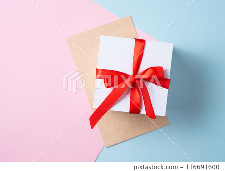 Flat lay of celebration. White gift box with red ribbon and craft envelope  116691600