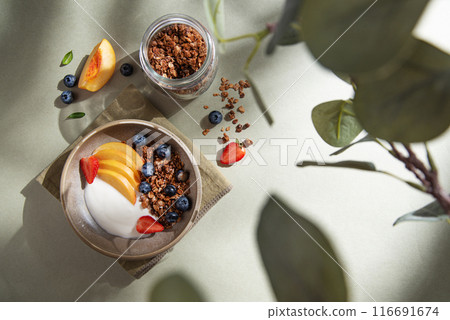 Delicious natural yogurt with homemade granola, berries, peach, in a bowl and jar with muesli Delicious natural yogurt with homemade granola, berries, peach, in a bowl and jar with muesli 116691674
