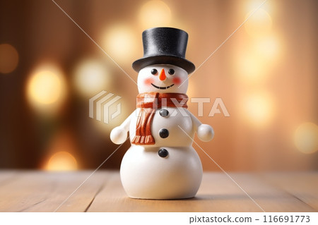 Snowman toy in top hat on a wooden surface with a bokeh background 116691773