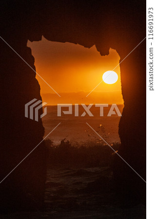 The setting sun peeping through keyhole arch 116691973