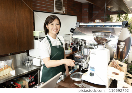 A female employee at a coffee shop making coffee A female employee at a coffee shop making coffee 116692792