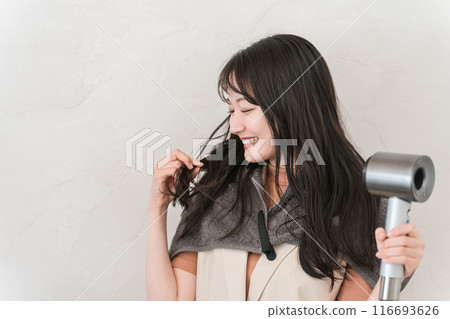 A woman blow-drying her hair with a hair dryer (tips of hair) 116693626