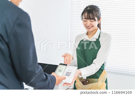 便利商店/超市的女店員在收銀、結帳、付款時出示二維碼。 116694109
