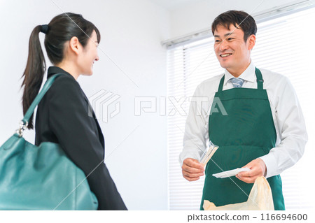 A male convenience store staff member bagging items at the cash register and a female shopper (chopsticks and wet towels) 116694600