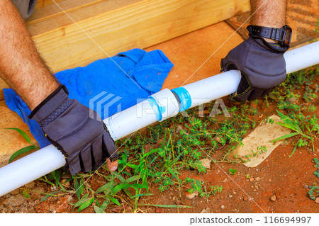 Plumbing building contractor installing glues plastic PVC pipes for laying water 116694997