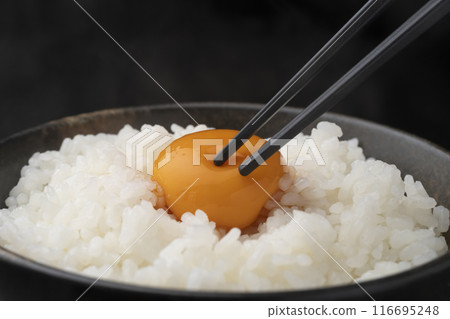 Raw egg on rice: Pick up the rice with chopsticks and crush the yolk with chopsticks Raw egg on rice: Pick up the rice with chopsticks and crush the yolk with chopsticks 116695248
