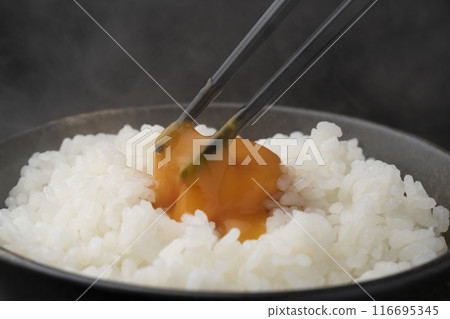 Raw egg on rice: Pick up the rice with chopsticks and crush the yolk with chopsticks Raw egg on rice: Pick up the rice with chopsticks and crush the yolk with chopsticks 116695345